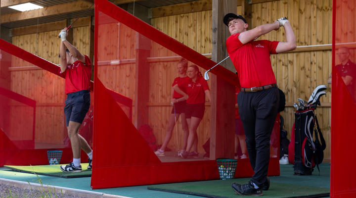 Male Student Practising In Golf Driving Range