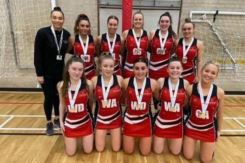 A group of netball players in red and black uniforms posing for a photo